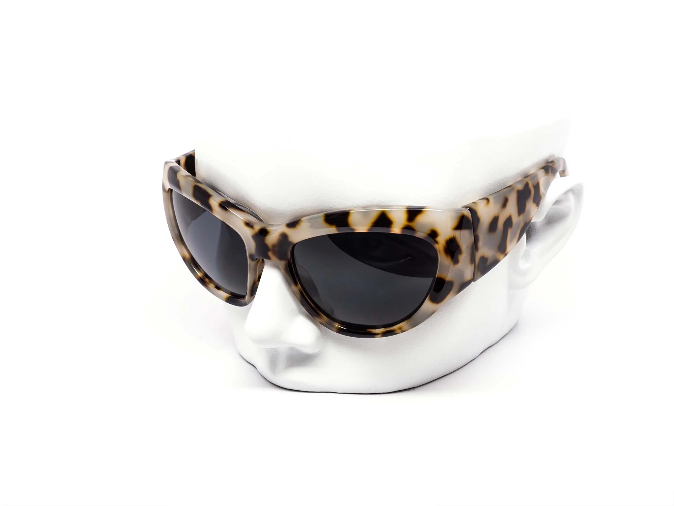 Sunglasses with leopard print frame on a white stand against a white background